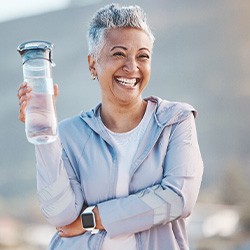 Woman smiling with water bottle on hike outside