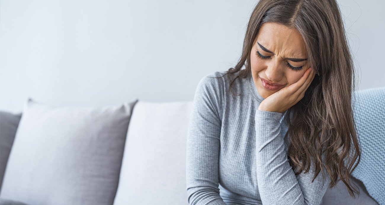 Woman in need of emergency dentistry holding jaw