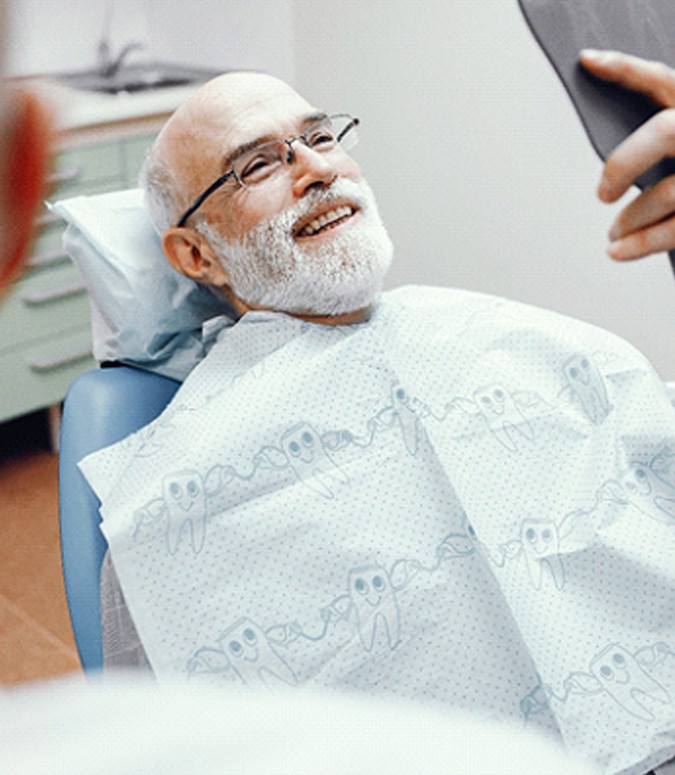 Man smiling in dental chair with dental crown in Englewood