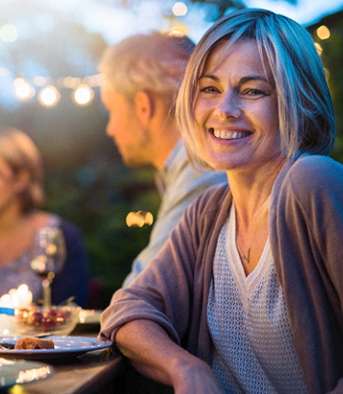 Woman smiling at dinner party with dental crown in Englewood