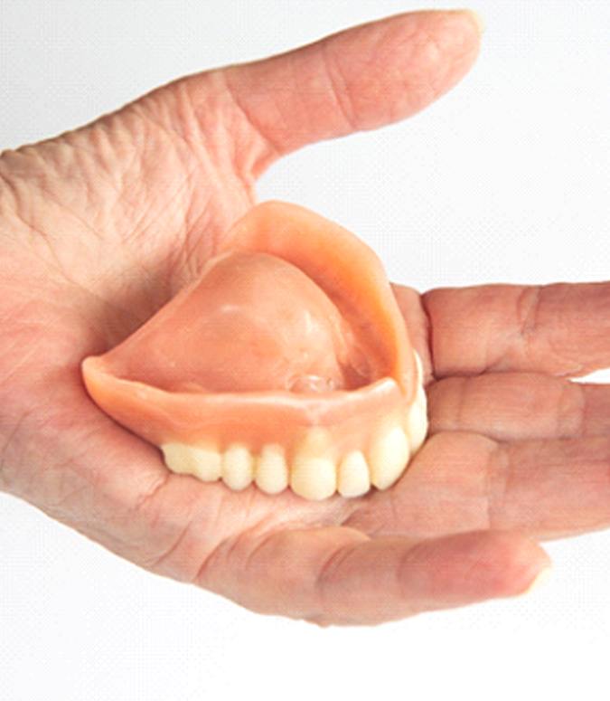 Hand holding a full denture