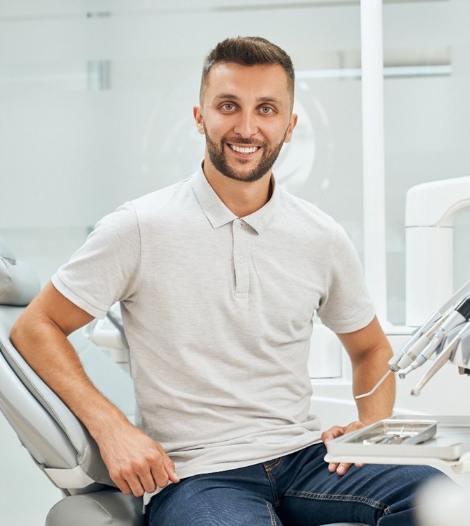Man in grey polo smiling in dental chair