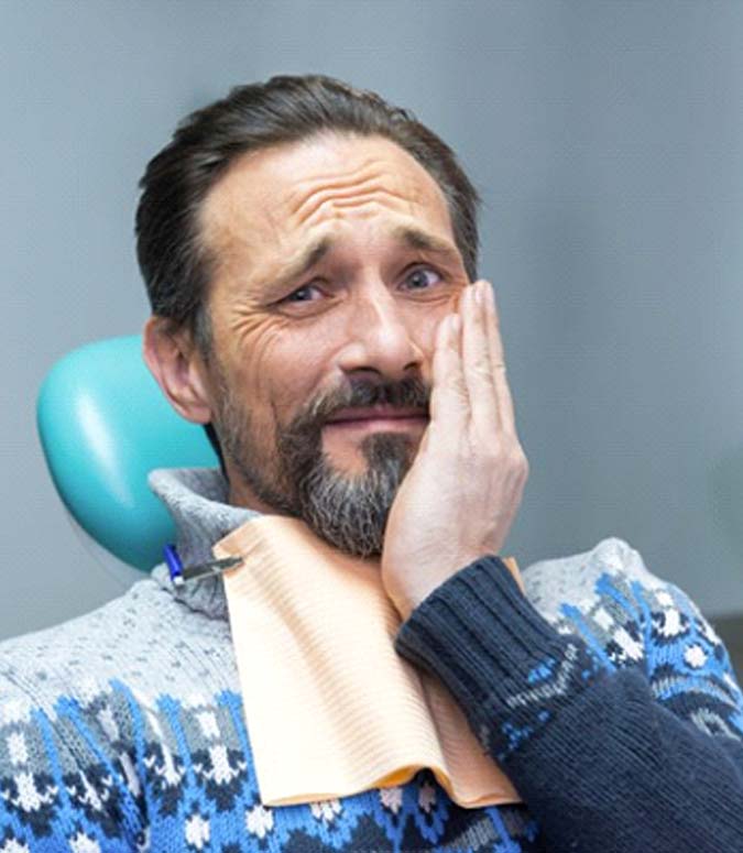 Man holding his cheek visiting Englewood emergency dentist