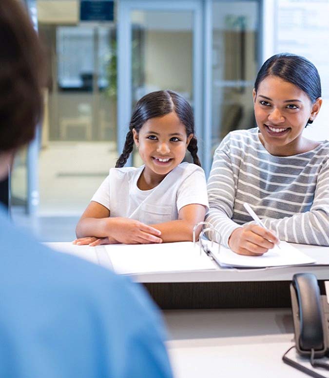 Smiling family paying for the cost of dental emergencies in Englewood