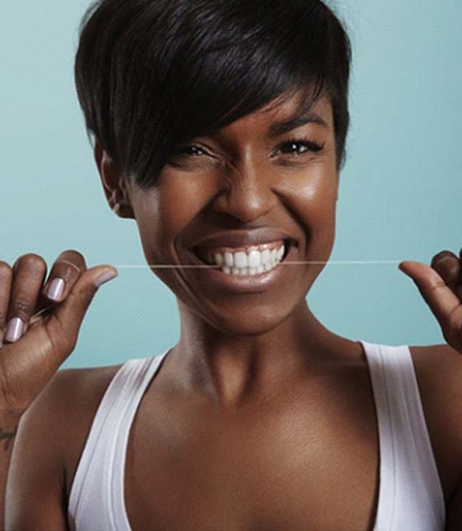 Woman flossing to avoid a toothache in Englewood