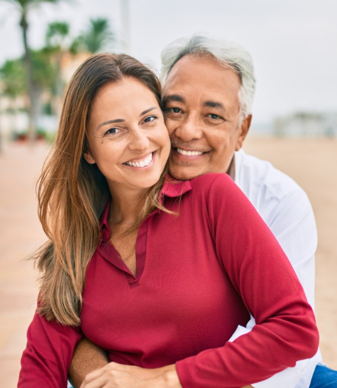 Man and woman smiling after dental implant tooth replacement