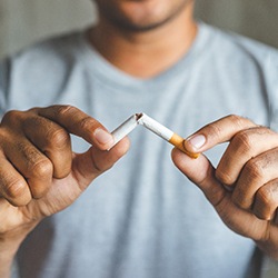 A man breaking a cigarette in half