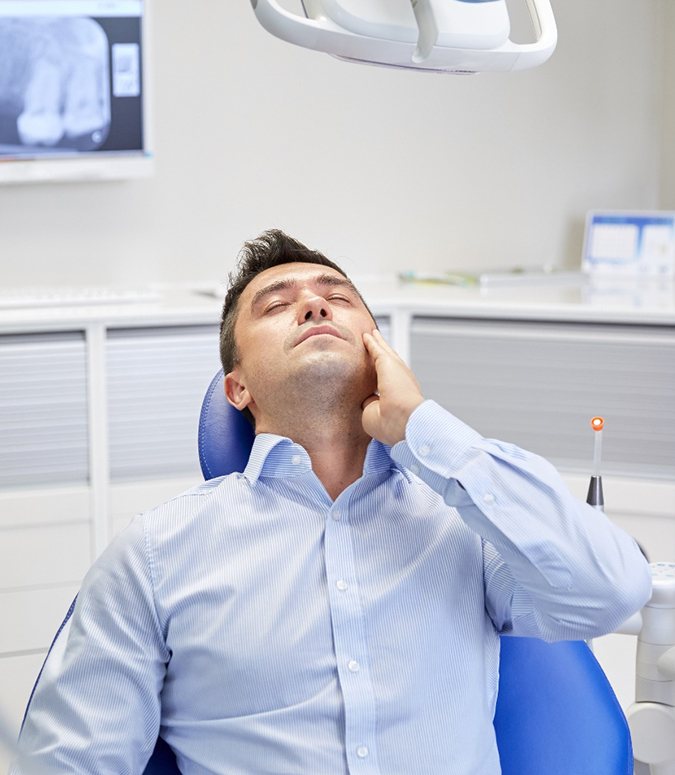 Man leaning back in dental chair with oral pain
