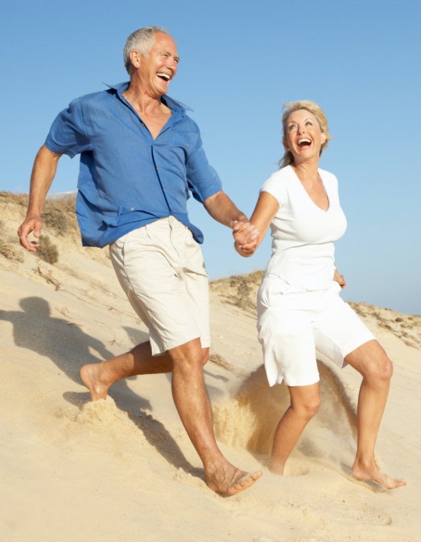 Smiling couple on the beach after receiving dental care