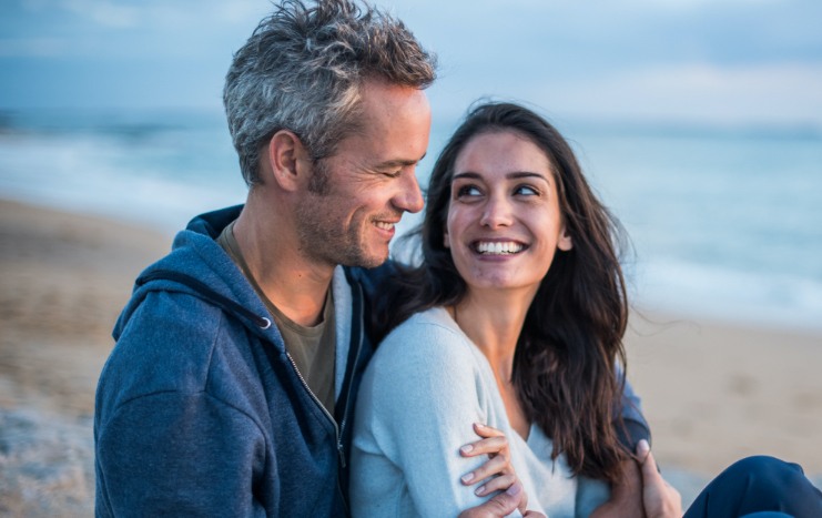 Man and woman smiling on the beach after cosmetic dentistry