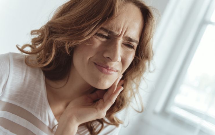 Woman in need of emergency dentistry holding jaw