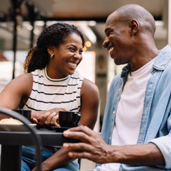 Couple smiling while enjoying cup of coffee outside