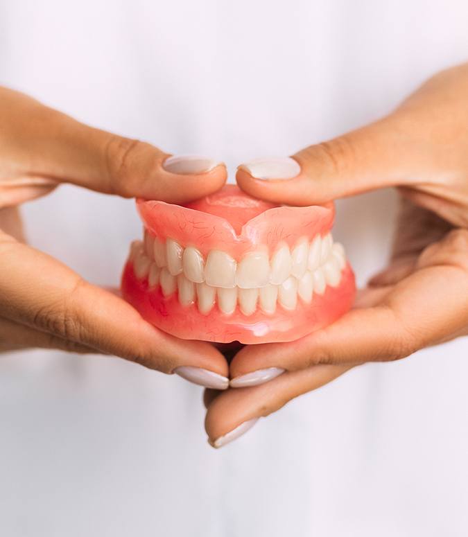 Hand holding full dentures