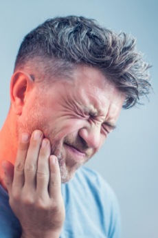 Man in need of emergency dentistry holding jaw in pain