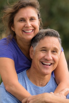 Man and woman smiling after replacing missing teeth