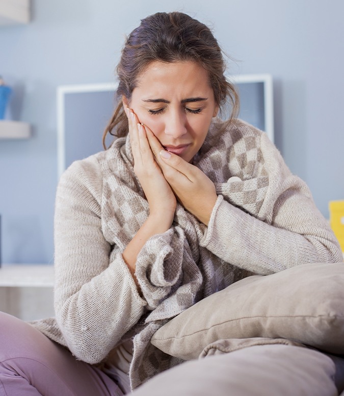 Woman in need of T M J diagnosis and treatment holding jaw in pain