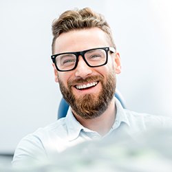 patient smiling while sitting in dental chair 