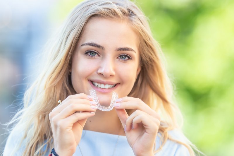 young woman holding her Invisalign aligner in the sun