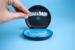 Hand holding clear Invisalign aligner. 